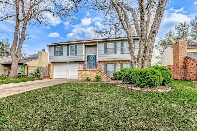 split foyer home with a garage, concrete driveway, brick siding, and a front lawn