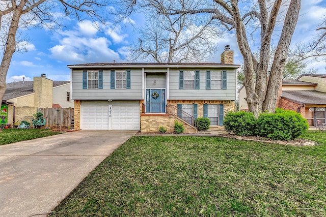 bi-level home with concrete driveway, a chimney, fence, a front lawn, and brick siding