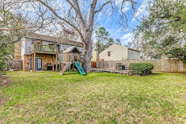 view of yard with a fenced backyard, a deck, and a playground