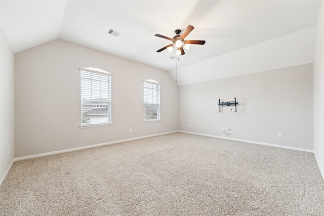 empty room with carpet floors, lofted ceiling, visible vents, ceiling fan, and baseboards