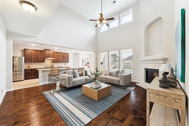 living room featuring ceiling fan, a glass covered fireplace, wood finished floors, and a wealth of natural light