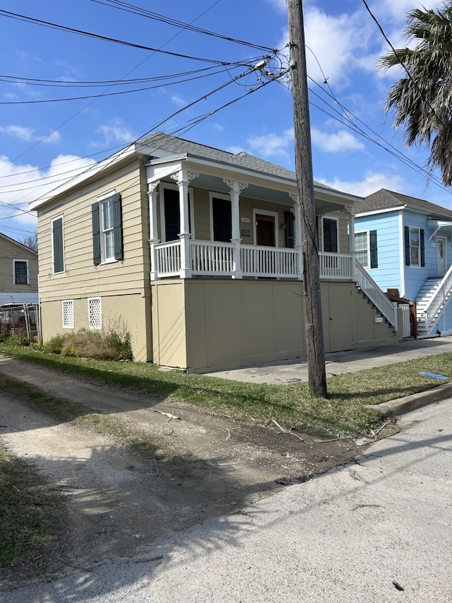 view of front of home featuring stairs, a porch, and roof with shingles