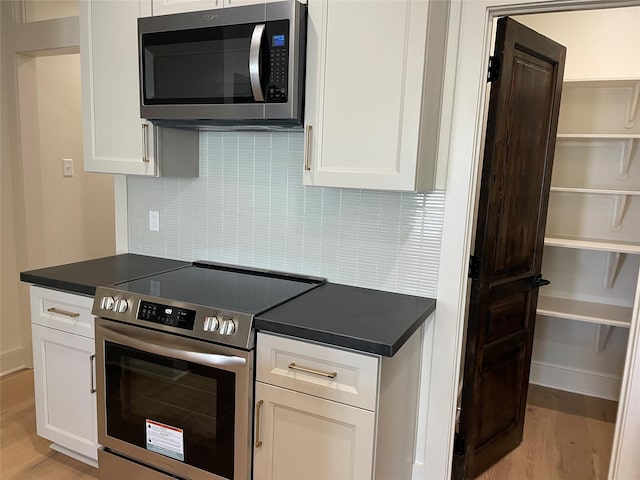 kitchen featuring stainless steel appliances, light wood-style floors, white cabinets, open shelves, and dark countertops