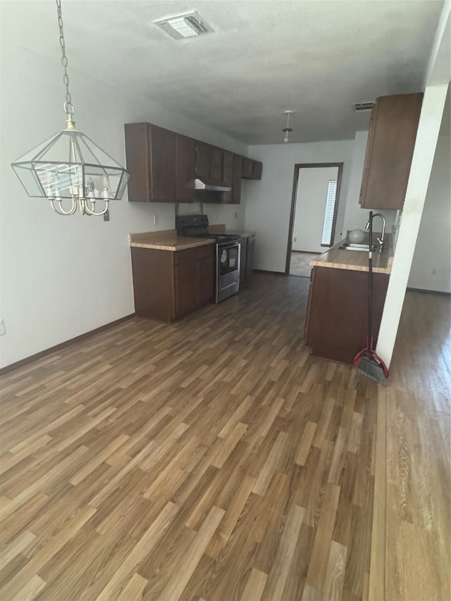 kitchen with electric range, visible vents, wood finished floors, light countertops, and a sink