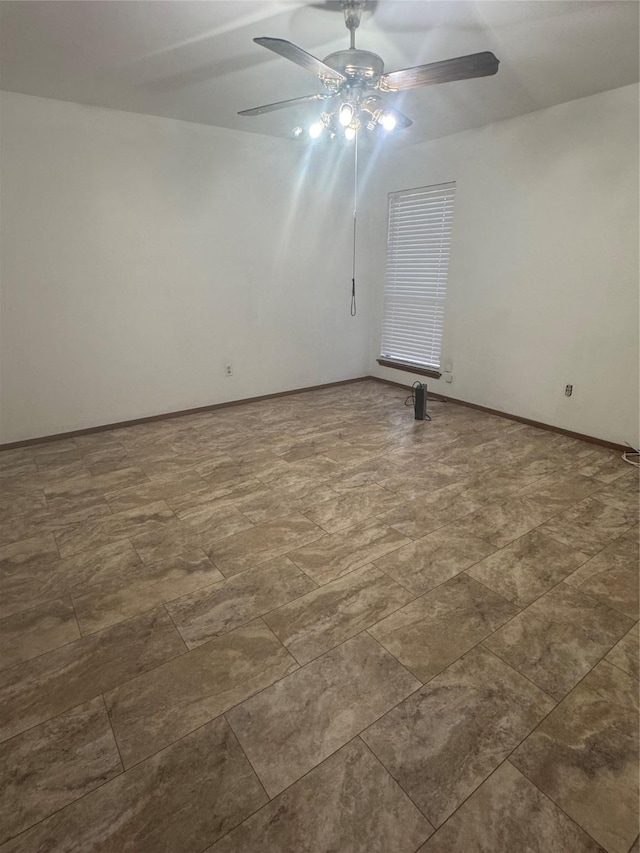 unfurnished room featuring a ceiling fan and baseboards