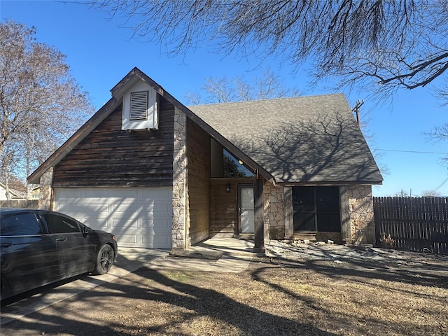 view of front facade featuring stone siding, fence, and driveway