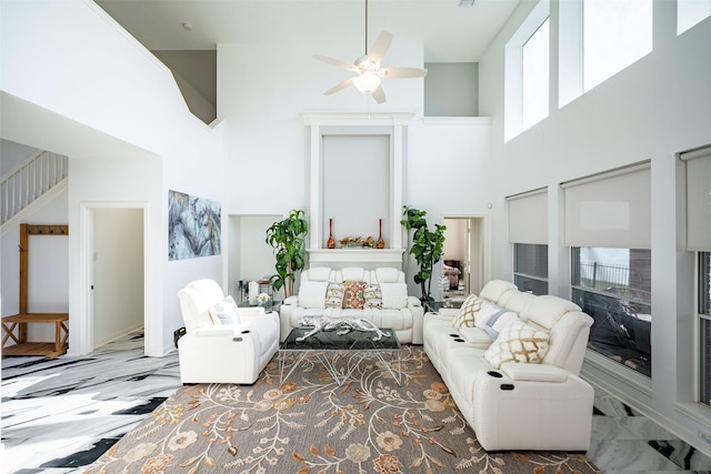 living area with stairs, ceiling fan, and a towering ceiling