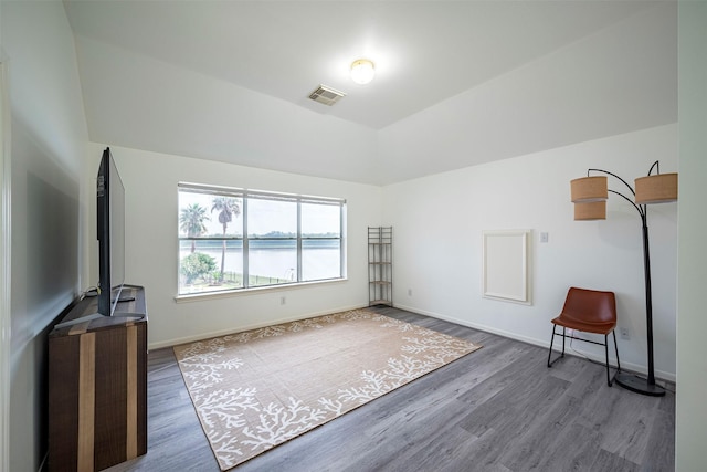 living area with lofted ceiling, baseboards, visible vents, and wood finished floors