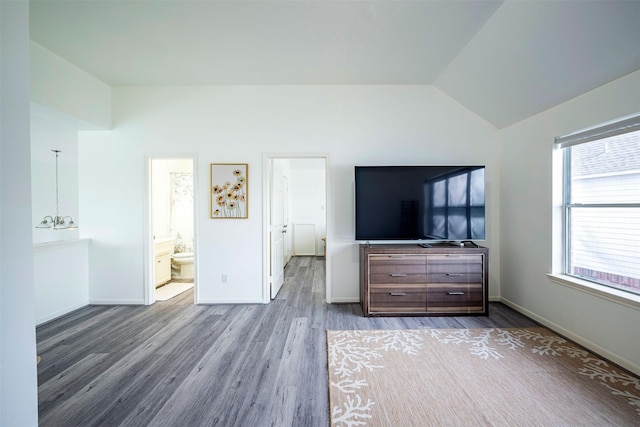 unfurnished bedroom with lofted ceiling, a chandelier, wood finished floors, and baseboards