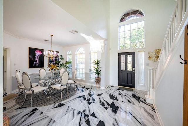 entrance foyer with baseboards, a high ceiling, stairs, crown molding, and a chandelier