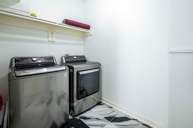 clothes washing area with laundry area, baseboards, and washer and dryer