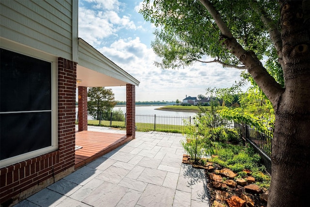 view of patio / terrace featuring a water view and fence