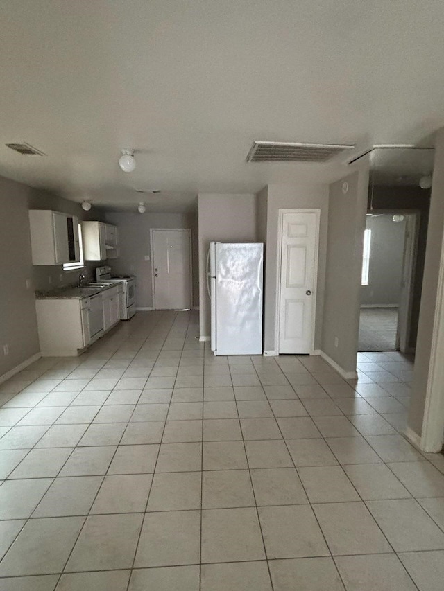 unfurnished living room featuring light tile patterned floors, baseboards, visible vents, and a sink