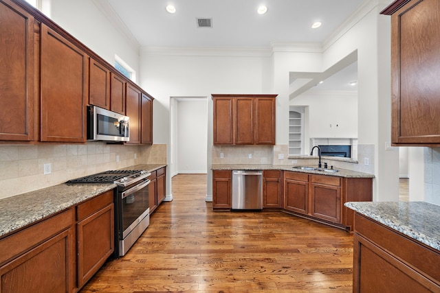 kitchen featuring visible vents, a sink, ornamental molding, stainless steel appliances, and dark wood-style flooring