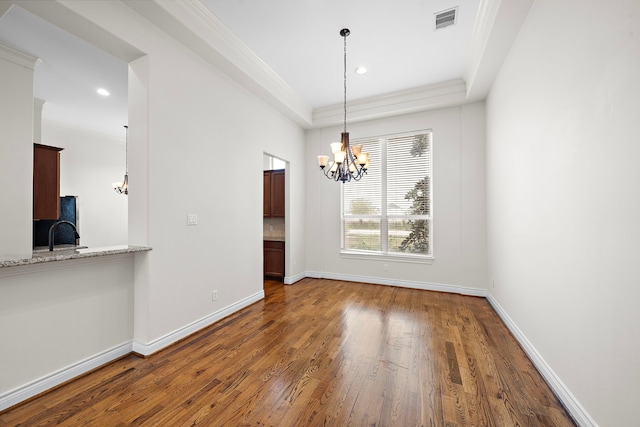 unfurnished dining area featuring a chandelier, visible vents, hardwood / wood-style flooring, and ornamental molding