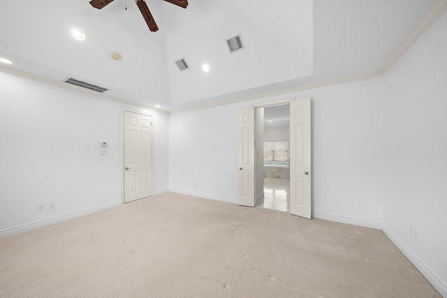 empty room with high vaulted ceiling, visible vents, and light carpet