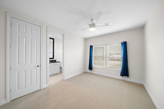 unfurnished bedroom with ceiling fan, baseboards, ensuite bathroom, and light carpet