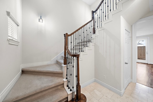 stairway with plenty of natural light and baseboards