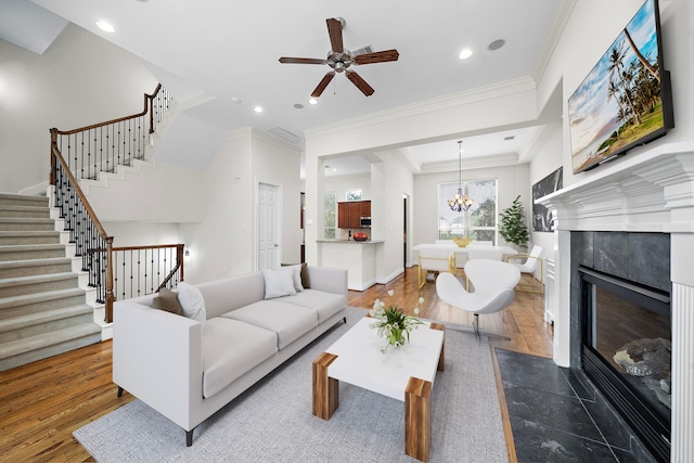 living area with a high end fireplace, crown molding, stairway, recessed lighting, and wood finished floors