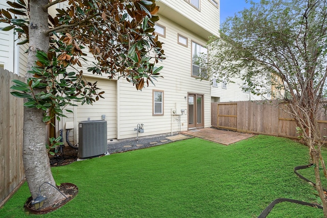 rear view of house with a patio, a yard, a fenced backyard, and central AC