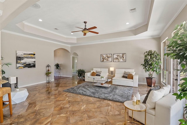 living room featuring visible vents, arched walkways, a raised ceiling, baseboards, and ceiling fan