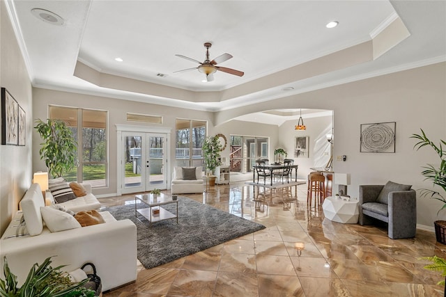 living area with a healthy amount of sunlight, a raised ceiling, and french doors