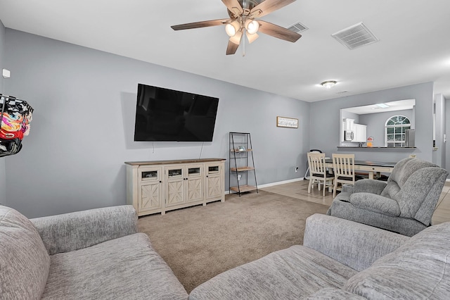 carpeted living area with a ceiling fan, visible vents, and baseboards