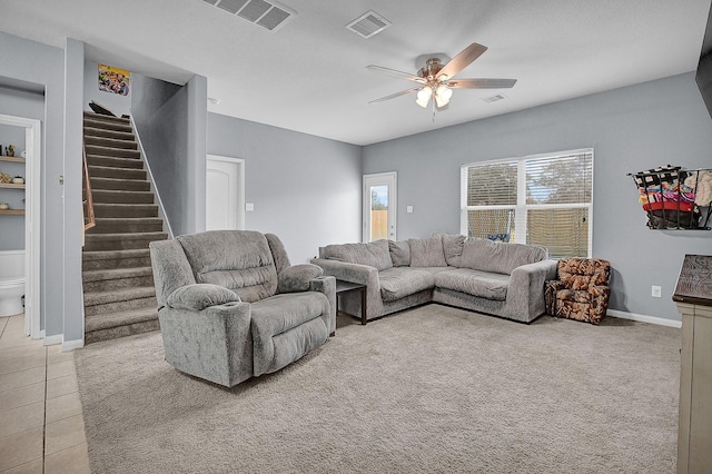 living area with light tile patterned floors, ceiling fan, stairway, and visible vents