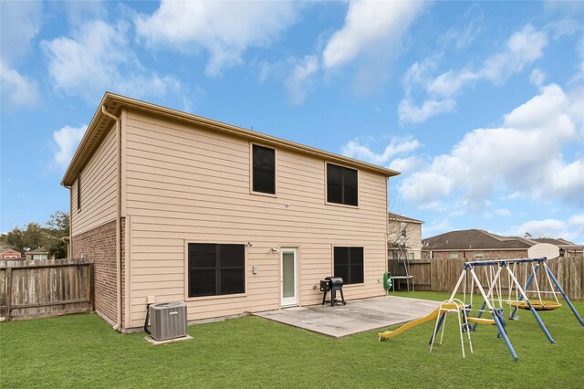 rear view of property featuring a lawn, a patio, a fenced backyard, a playground, and central AC