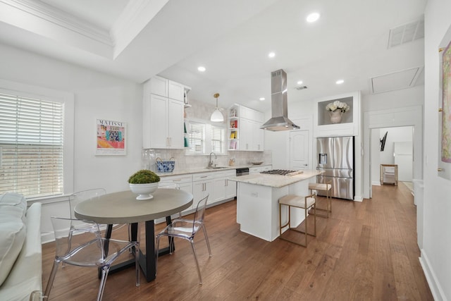 kitchen with island range hood, a kitchen island, decorative light fixtures, stainless steel appliances, and white cabinetry