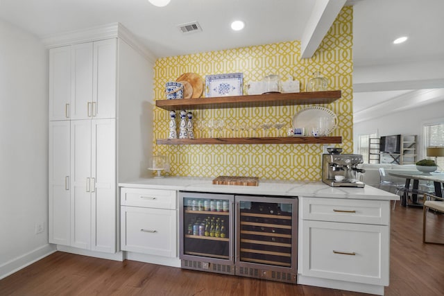 bar featuring wallpapered walls, beverage cooler, visible vents, dark wood finished floors, and a bar