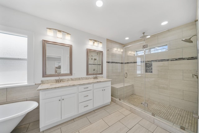 bathroom with double vanity, a freestanding tub, a stall shower, and a sink