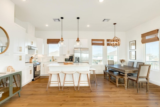 kitchen with light countertops, appliances with stainless steel finishes, white cabinets, and under cabinet range hood