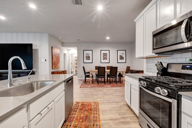 kitchen with visible vents, white cabinets, appliances with stainless steel finishes, light countertops, and a sink