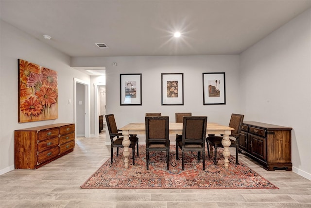 dining area featuring light wood finished floors, baseboards, and visible vents