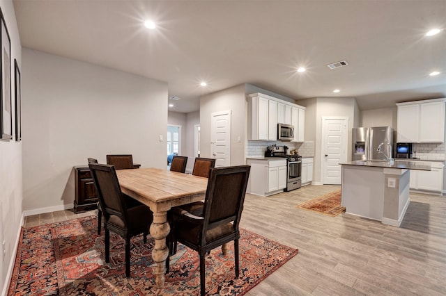 dining area featuring light wood-style floors, recessed lighting, visible vents, and baseboards