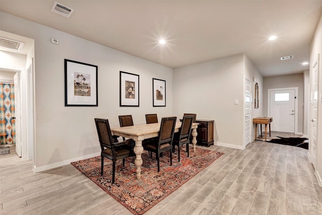 dining space with baseboards, visible vents, and light wood finished floors