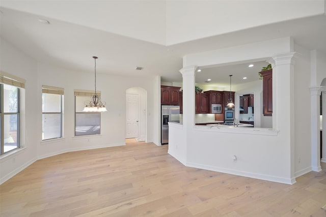 interior space featuring recessed lighting, hanging light fixtures, appliances with stainless steel finishes, light wood-type flooring, and ornate columns