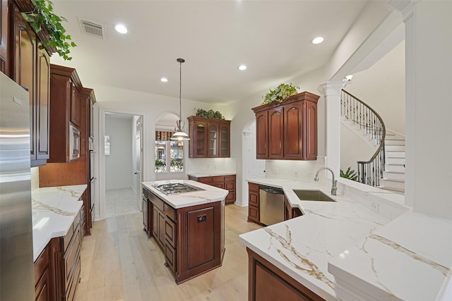 kitchen featuring light wood finished floors, visible vents, decorative backsplash, stainless steel appliances, and a sink