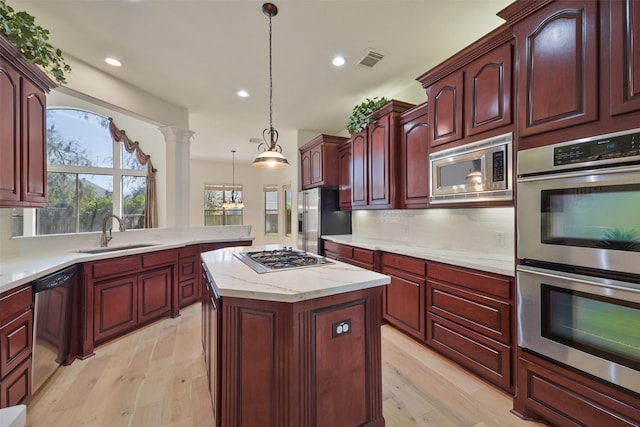 kitchen featuring reddish brown cabinets, stainless steel appliances, a sink, and ornate columns