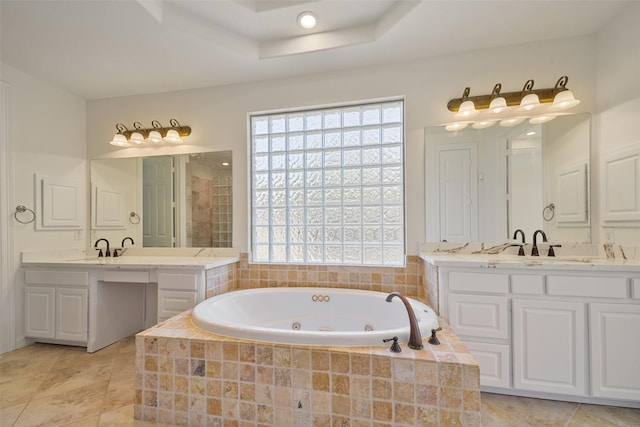 bathroom featuring a whirlpool tub, a tray ceiling, a sink, and two vanities