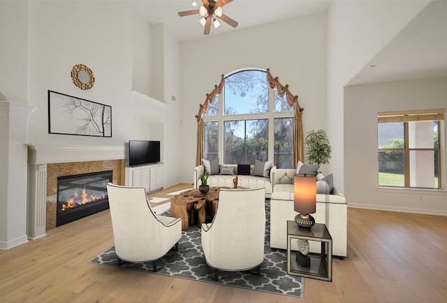 dining space with a high ceiling, a fireplace, baseboards, and wood finished floors