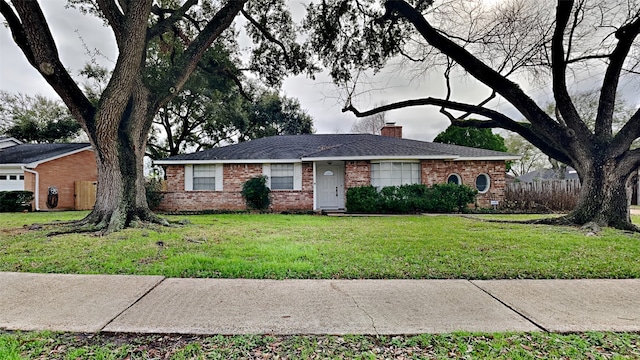 ranch-style home featuring a front yard, a shingled roof, a chimney, and brick siding