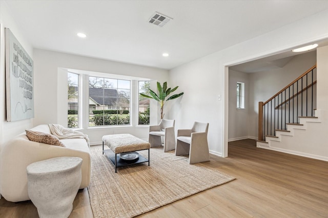 sitting room featuring baseboards, visible vents, stairway, wood finished floors, and recessed lighting