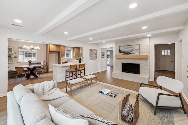 living area with beam ceiling, light wood-type flooring, visible vents, and recessed lighting