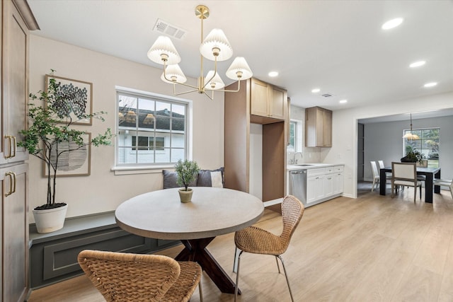 dining space with a healthy amount of sunlight, an inviting chandelier, light wood-style flooring, and visible vents