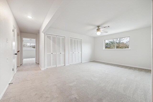 unfurnished bedroom featuring multiple windows, baseboards, and two closets