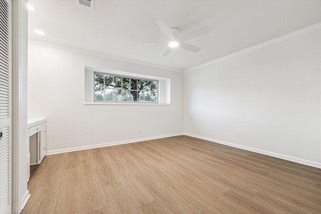 spare room with light wood-type flooring, a ceiling fan, baseboards, and crown molding