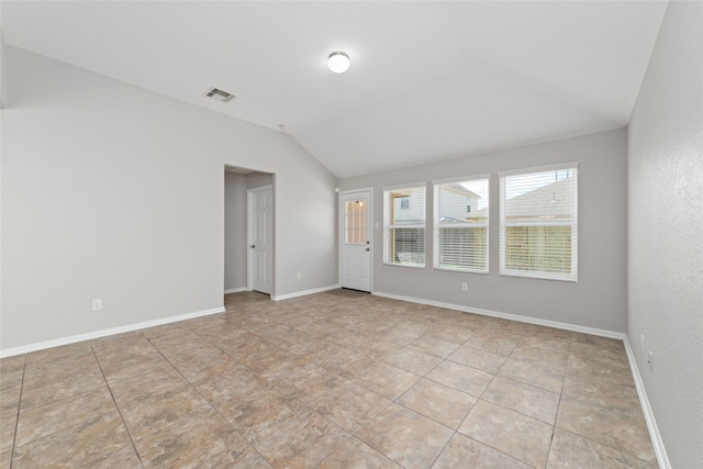 empty room featuring lofted ceiling, light tile patterned floors, baseboards, and visible vents