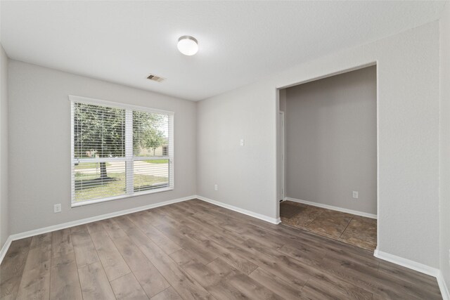 empty room with baseboards, visible vents, and dark wood-type flooring